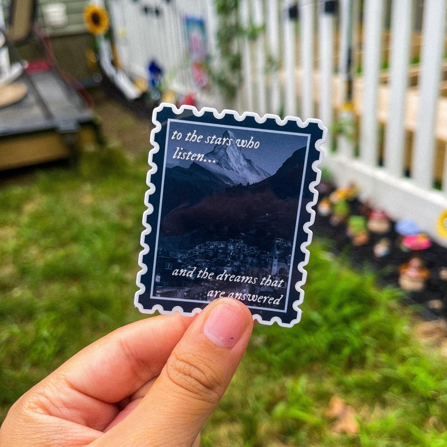 Sticker in shape of postage stamp with a mountain city and the quotes "to the stars who listen and the dreams that are answered" inspired by ACOTAR.