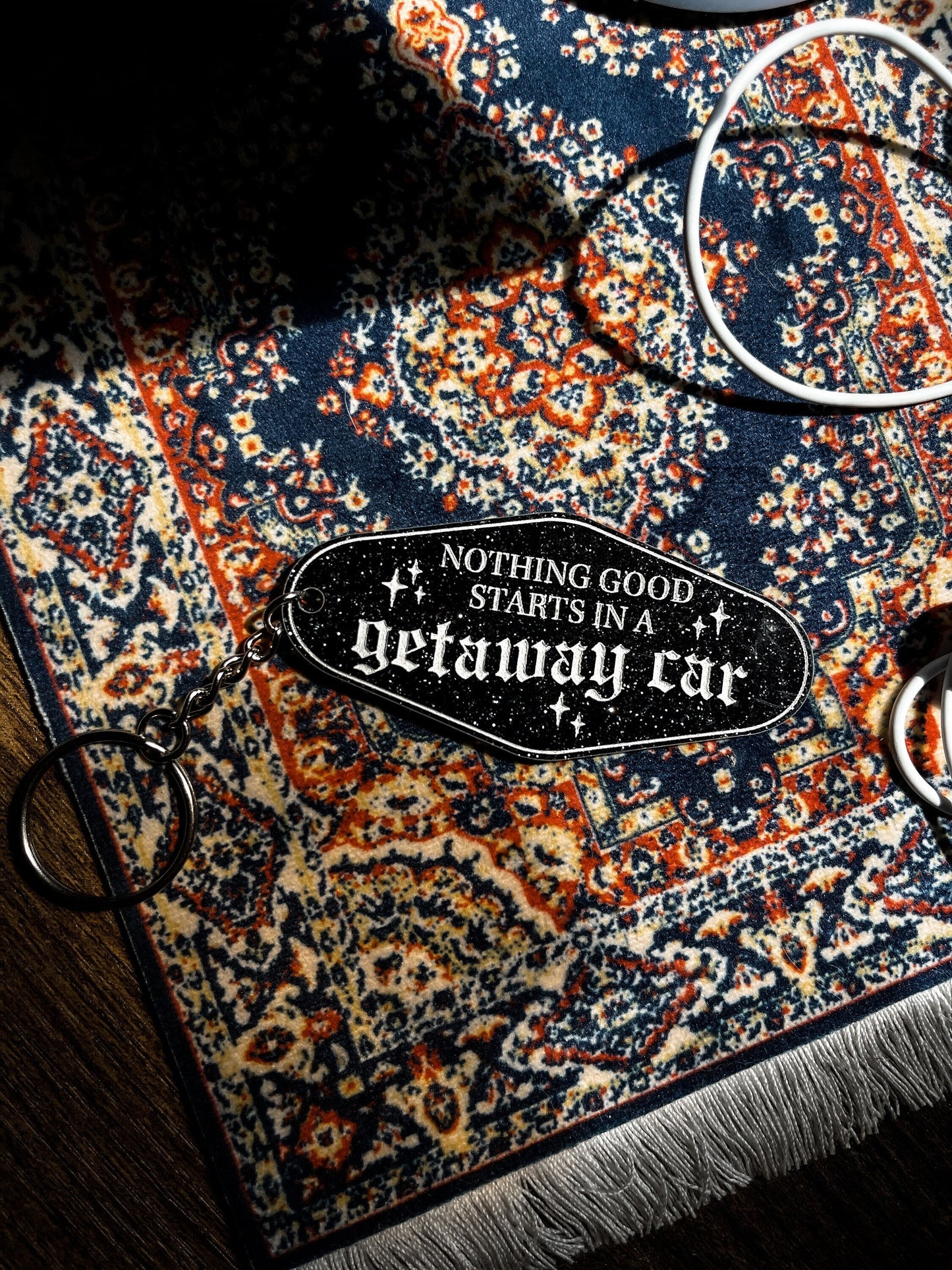 black, sparkly motel keychain with the lyrics "nothing good starts in a getaway car" inspired by taylor swift's album reputation.