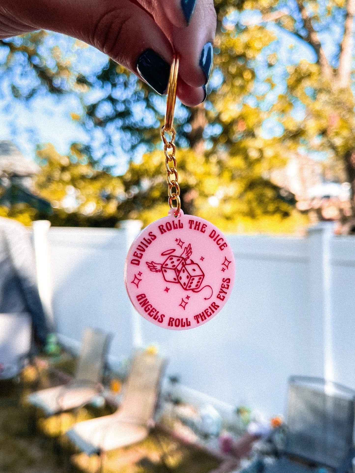 Pink circle acrylic keychain with the Taylor Swift lyrics "devils roll the dice, angels roll their eyes" engraved around dice. 