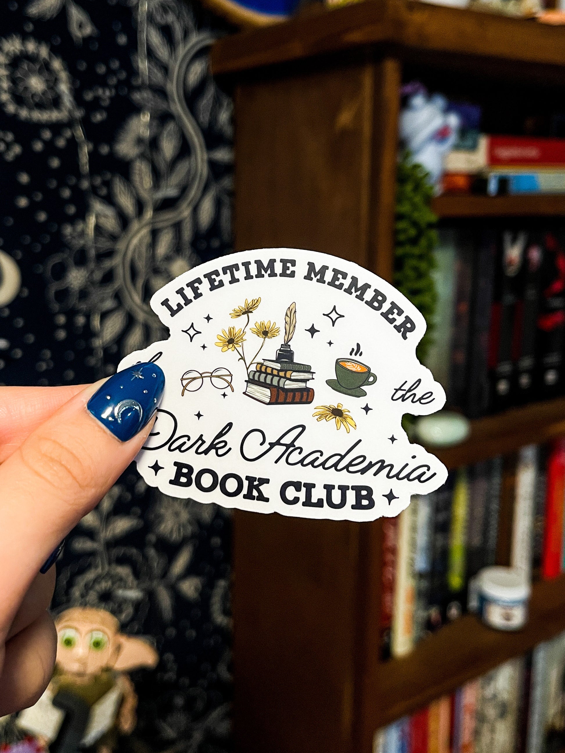 Transparent sticker with the words "lifetime member of the dark academia book club" and illustrations of flowers, books and coffee. 