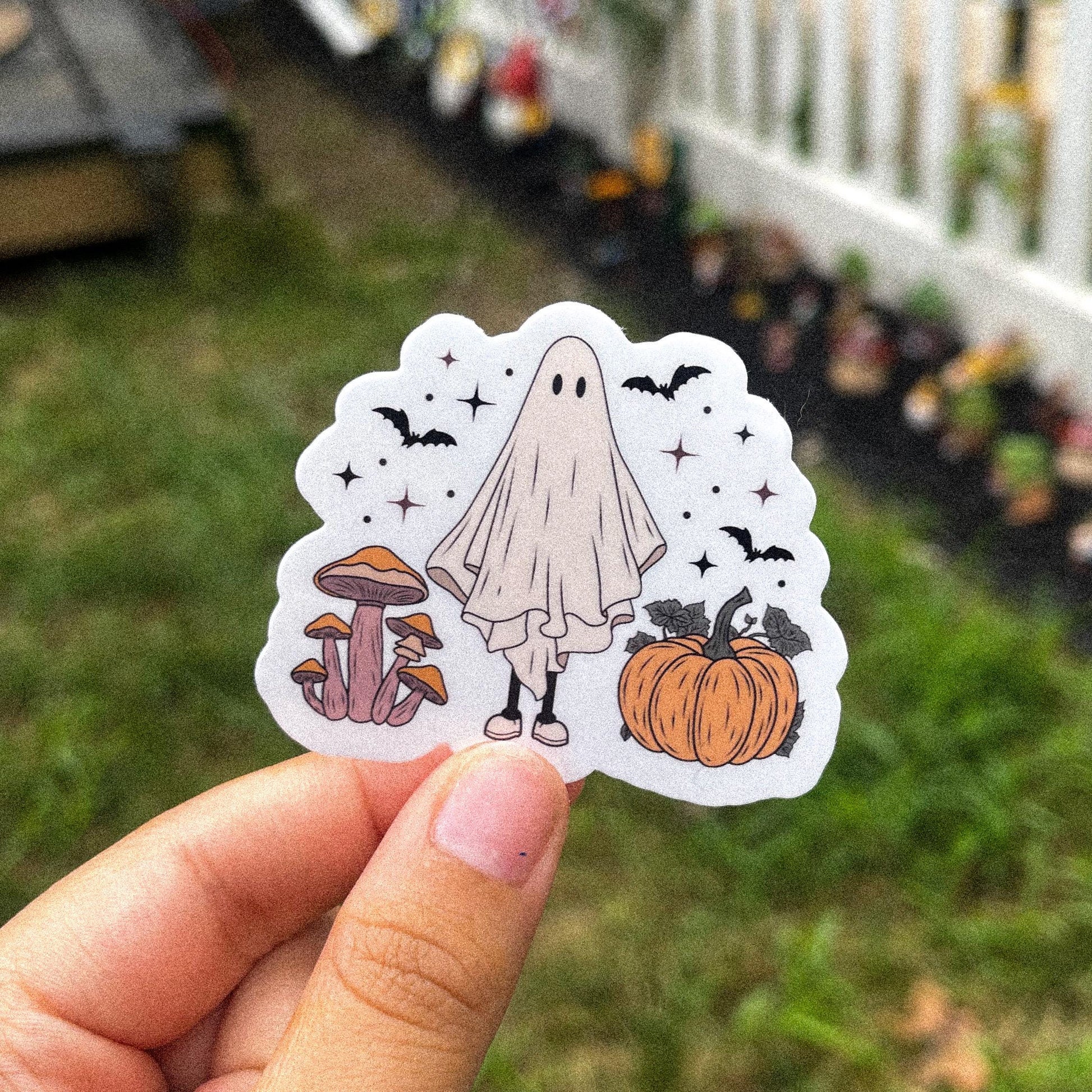 Cozy aesthetic sticker of a ghost surrounded by mushrooms, pumpkins, and bats. 