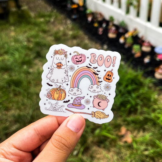 A cozy Halloween sticker with different Halloween-inspired designs such as a cauldron, broomstick, witch hat, pumpkins, ghost, a rainbow, bats, and webs. 