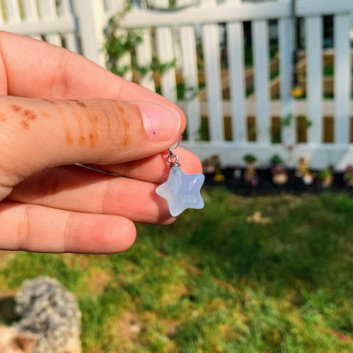 A Kawaii aesthetic small blue star phone charm dangling from the USB-C port of an iPhone.