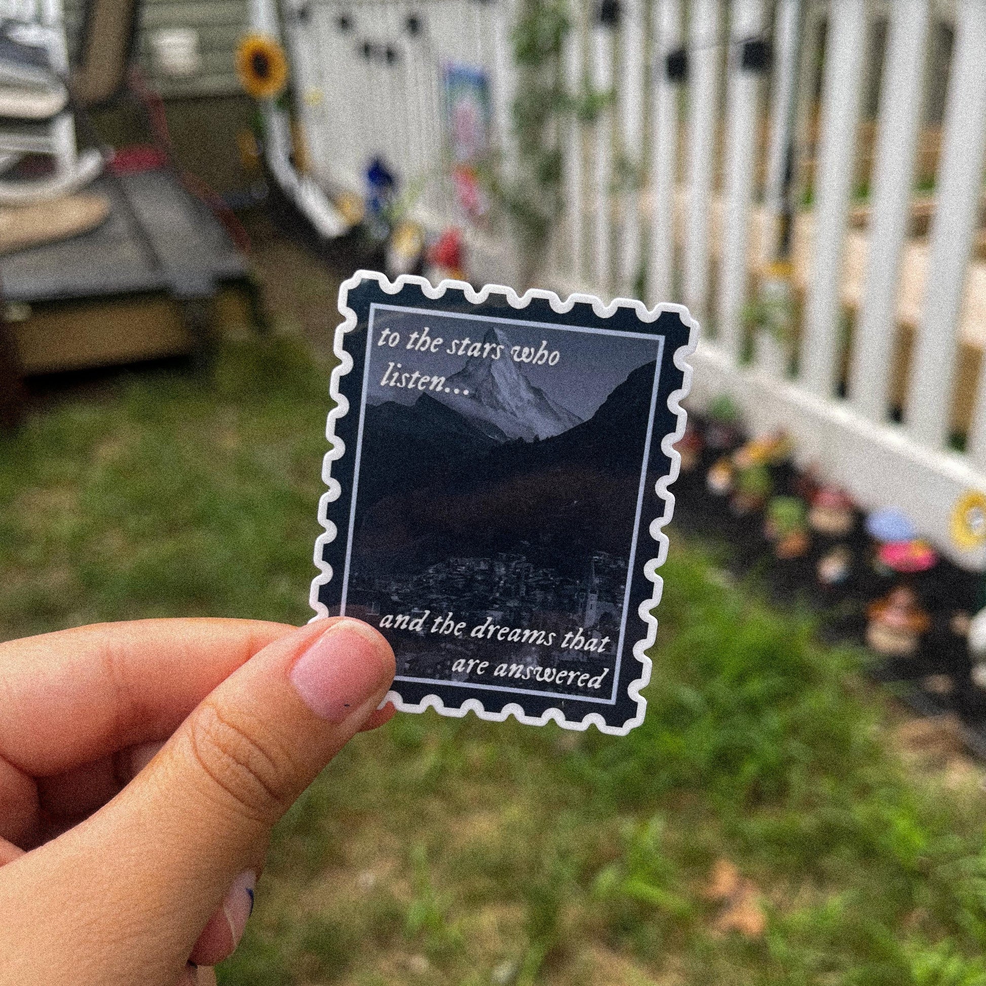 Sticker in shape of postage stamp with a mountain city and the quotes "to the stars who listen and the dreams that are answered" inspired by ACOTAR. 