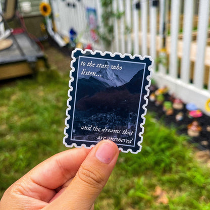 Sticker in shape of postage stamp with a mountain city and the quotes "to the stars who listen and the dreams that are answered" inspired by ACOTAR. 